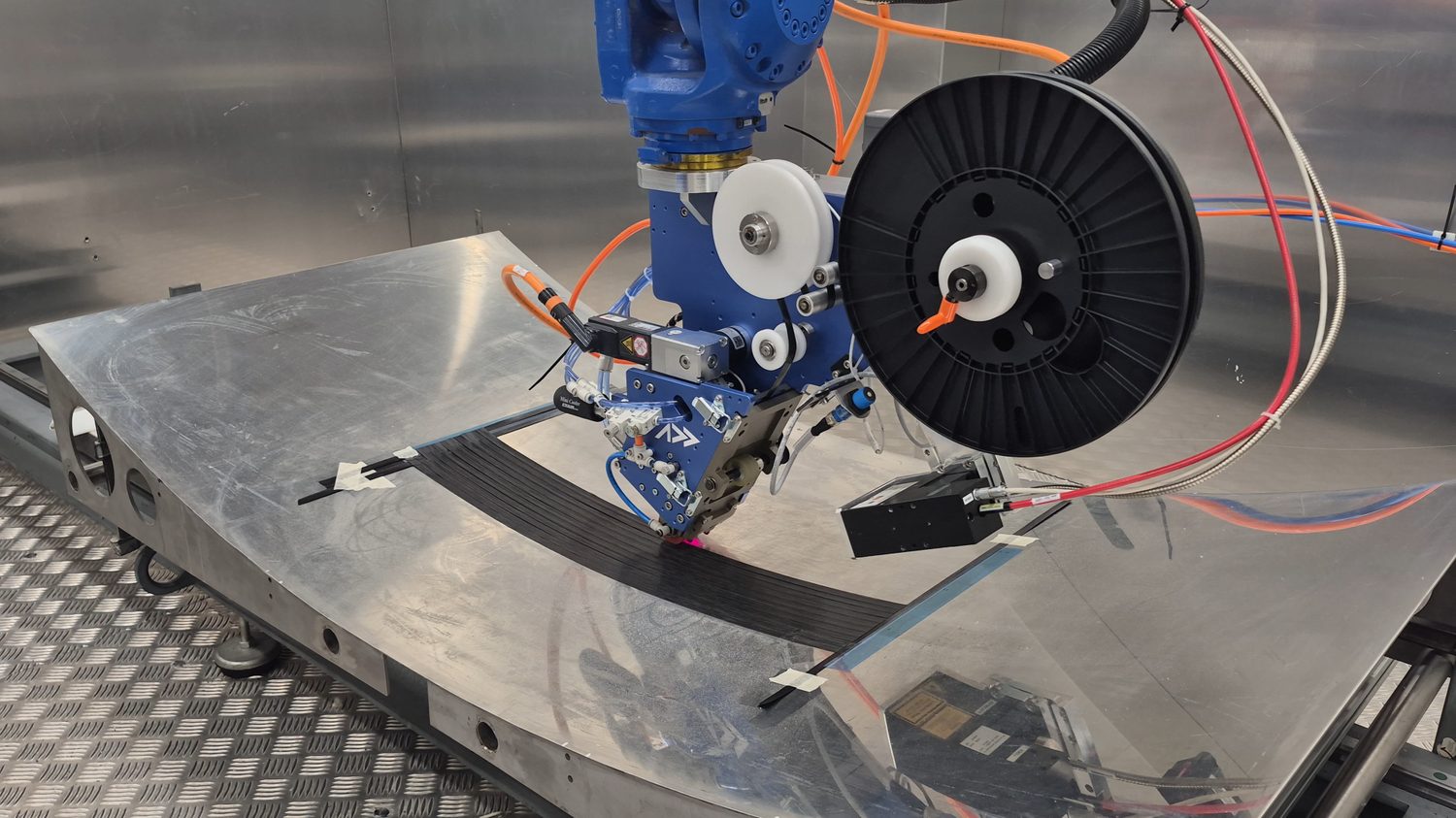The Addcomposites AFP-XS head placing tow along a contoured tool, the band following the surface as one continuous path.