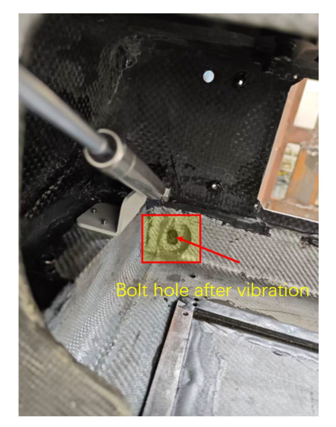 Post-test inspection inside the frame, with the elongated bolt hole at the display bracket attachment highlighted where the metal meets the laminate.