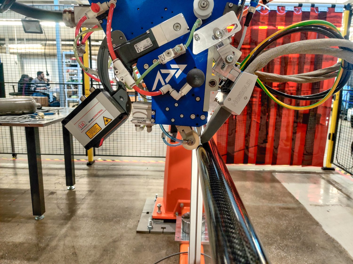 An AFP-XS head laying carbon fibre onto a tubular mandrel — placing the ply architecture that governs how a crush tube absorbs energy.