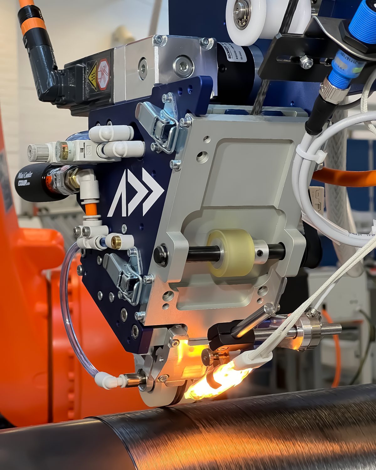 Addcomposites AFP-XS head depositing continuous carbon fibre tow onto a rotating mandrel, with the heat source and compaction roller consolidating the tape in situ to achieve low void content.